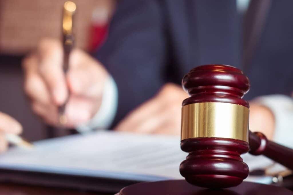 Close-up of a wooden gavel on a desk with a document in the background, suggesting a legal decision or signing.